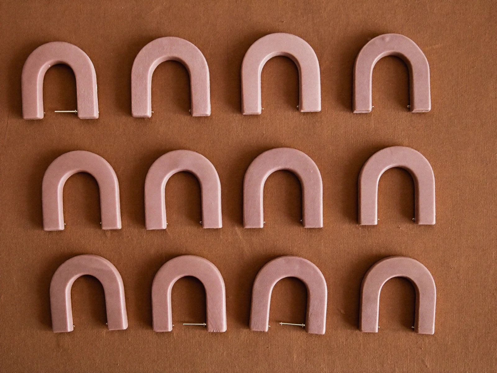 Twelve identical clay earring pairs in rows.